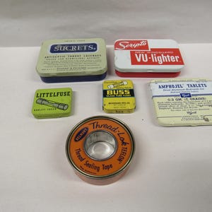 May include: Collection of vintage tins and containers. Includes a Sucrets tin, a Scripto VU-lighter, a Littelfuse box, a Buss glass tube fuses box, an Amphojel Tablets box, and a Thread-Lok Teflon tape roll.