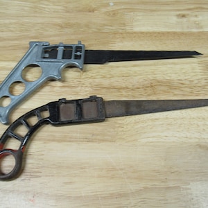 May include: Two hand saws with different colored handles. The top saw has a silver handle and a black blade. The bottom saw has a black handle with red accents and a rusty blade.