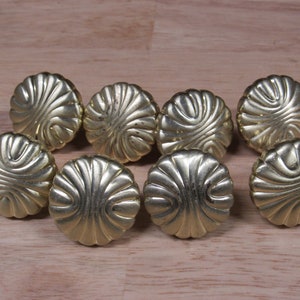May include: Eight gold-toned cabinet knobs with a decorative, raised, fan-shaped design.