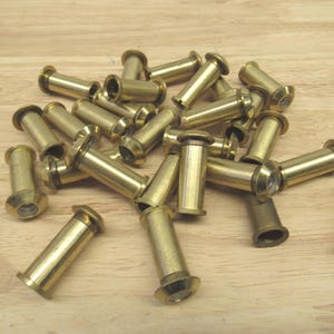May include: A pile of brass door peepholes, a security feature for doors. The peepholes are cylindrical with a small lens at one end.