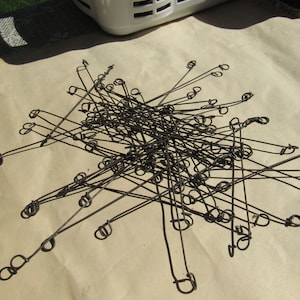 May include: A pile of rusty metal wire loops with a small loop at the end of each wire. The wires are tangled together and are laying on a brown paper surface.