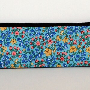 May include: A blue zippered pencil case with a floral print featuring pink, yellow, and blue flowers on a light blue background.
