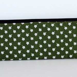 May include: A green zippered pouch with a white floral pattern.