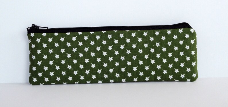 May include: A green zippered pouch with a white floral pattern.