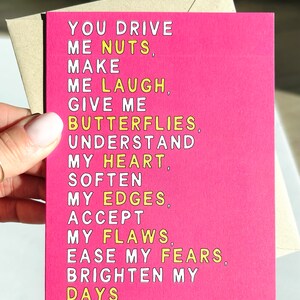 May include: Pink card with yellow text that reads "You drive me nuts, make me laugh, give me butterflies, understand my heart, soften my edges, accept my flaws, ease my fears, brighten my days."