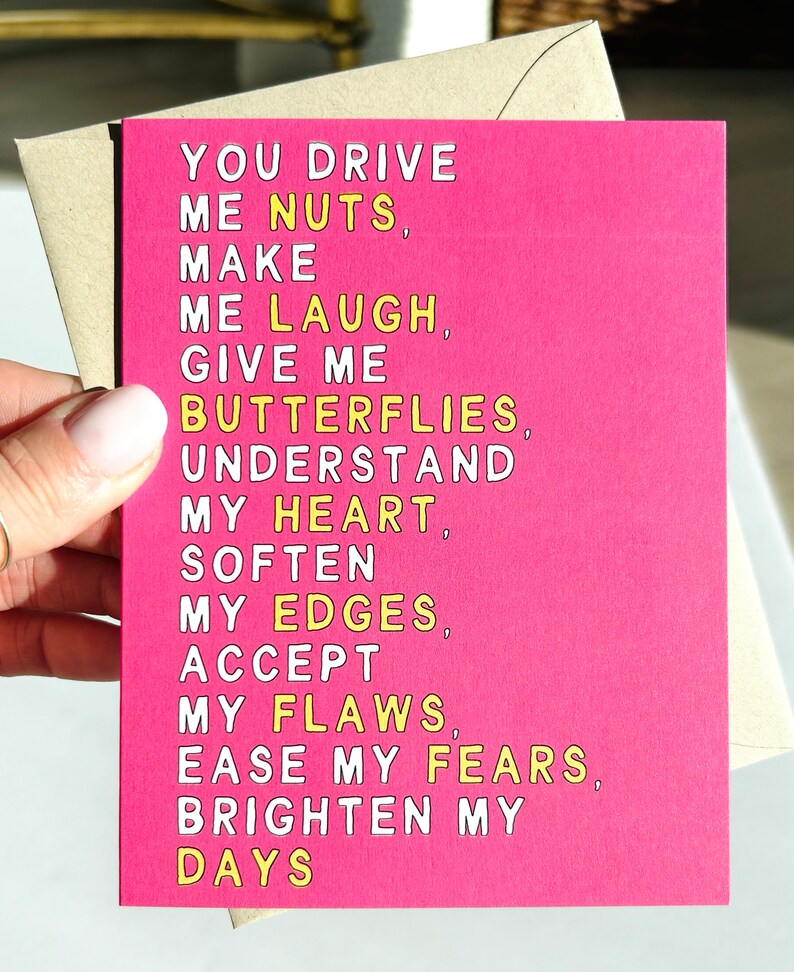 May include: Pink card with yellow text that reads "You drive me nuts, make me laugh, give me butterflies, understand my heart, soften my edges, accept my flaws, ease my fears, brighten my days."