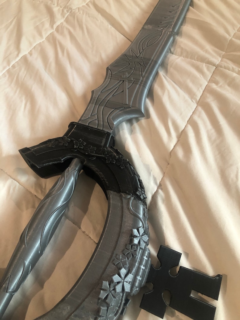 May include: A gray 3D printed sword with intricate details and a black handle. The sword has a curved blade and a decorative design on the hilt.