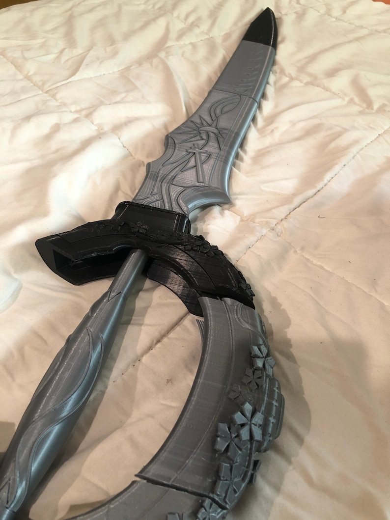 May include: A gray 3D printed sword with a black handle and intricate details. The sword is curved and has a floral design on the blade.