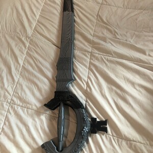 May include: A gray 3D printed sword with intricate details and a curved handle.