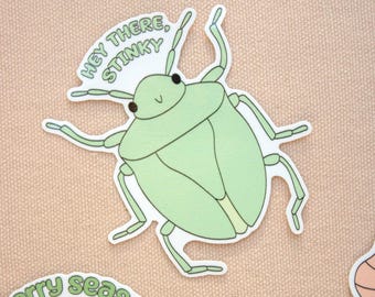 May include: A light green sticker featuring a cartoon stink bug with the text "Hey there, Stinky." The bug has a rounded body, six legs, and two antennae. The sticker is on a light tan background.