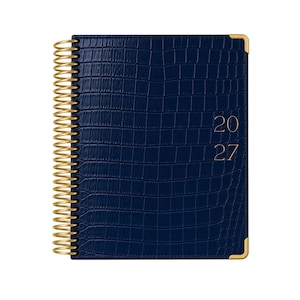 May include: A navy blue planner with a textured crocodile skin pattern, featuring gold-colored spiral binding and gold-colored metal corner protectors. The front cover displays the year 2027 in gold-colored lettering on the right side.
