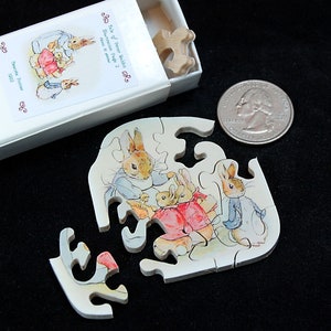 以下が含まれることがあります： ピーターラビットとその家族を描いた小さな木製ジグソーパズル。パズルは、「The Tale of Peter Rabbit」と「Beatrix Potter」の文字が印刷された白い箱に入っています。パズルは部分的に組み立てられており、本の登場人物が描かれています。