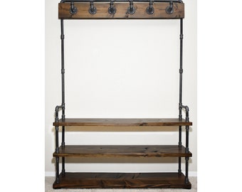 May include: A hall tree featuring three horizontal dark stained wooden shelves supported by a black industrial pipe frame. The upper section includes a matching wooden board with six black metal hooks attached to the pipe structure for hanging items.