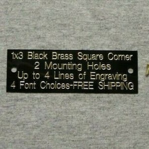 May include: Black brass square corner plaque with 2 mounting holes. The plaque has the text "1x3 Black Brass Square Corner 2 Mounting Holes Up to 4 Lines of Engraving 4 Font Choices-FREE SHIPPING".
