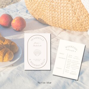 May include: Two white cards with text on a white tablecloth. The first card says "Seashells & Wedding Bells" with a seashell graphic. The second card says "Weekend Events" with a list of events for Friday, Saturday, and Sunday.