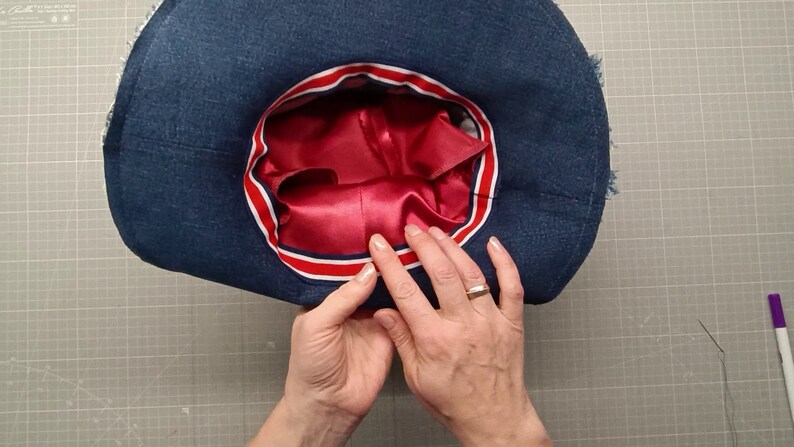 May include: A blue denim hat with a red satin lining and a red, white, and blue ribbon trim.