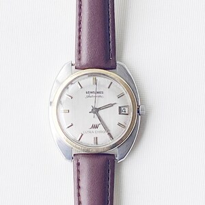 May include: A silver and gold Longines Ultra Chron watch with a brown leather band. The watch face is white with black Roman numeral hour markers and black hands.