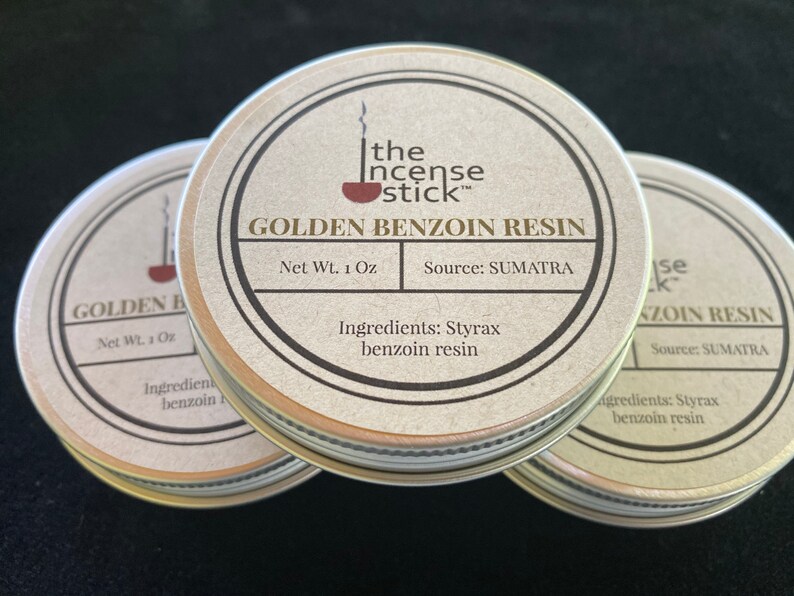 May include: Three round metal tins with lids, each containing golden benzoin resin. The label on the front tin reads "The Incense Stick" and "Golden Benzoin Resin". The label also states "Net Wt. 1 Oz" and "Source: SUMATRA". The label on the front tin also lists the ingredients as "Styrax benzoin resin".