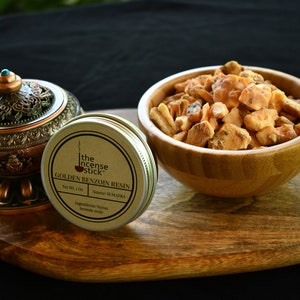 May include: A small tin container of golden benzoin resin from Sumatra, labelled "The Incense Stick Golden Benzoin Resin". The resin is also shown in a wooden bowl.
