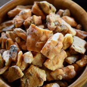May include: A wooden bowl filled with light brown and white resin pieces.
