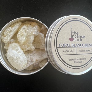 May include: A small tin container filled with white copal blanco resin. The label on the tin reads "the incense stick™ COPAL BLANCO RESIN Net Wt. 1 Oz Source: MEXICO Ingredients: Bursera bipinnata"