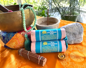 Può includere: Due confezioni di incenso di fiori tibetano rosa e blu con il testo "Tibetan Flower Kathgodokori Incense" e una descrizione dell'incenso. Le confezioni sono su un tavolo con una ciotola cantate, una mala, una roccia e un piccolo bruciatore di incenso.
