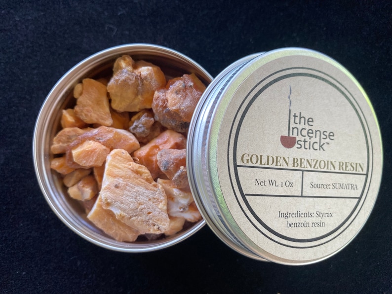 May include: A small tin container with a lid, containing golden benzoin resin. The lid has a label that reads "the incense stick" and "Golden Benzoin Resin". The label also states "Net Wt. 1 Oz" and "Source: SUMATRA". The ingredients are listed as "Styrax benzoin resin".