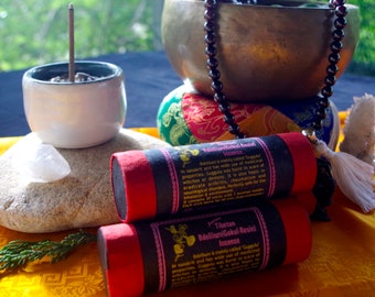 Può includere: Due bastoncini di incenso rosso e nero con la scritta "Incenso tibetano Bdellium Gokul-Resin". I bastoncini sono impilati uno sopra l'altro e sono su un tessuto giallo con un fiocco bianco.