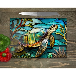 May include: A stained glass style chopping board featuring a sea turtle swimming in a blue and green ocean with seaweed and coral.