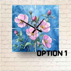 Peut inclure: Un cadran d'horloge aquarelle avec des fleurs roses et un fond bleu. Les aiguilles de l'horloge sont noires et le cadran est étiqueté "OPTION 1".