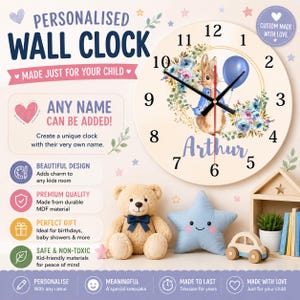 May include: A round wall clock featuring a rabbit illustration, a blue balloon, and floral accents. The clock face displays black numbers from 1 to 12, black hands, and the name Arthur in purple script. Text on the clock includes Personalised Wall Clock.