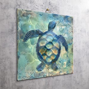 May include: A square wall plaque featuring a sea turtle with a blue and gold patterned shell. The turtle is centered against a background of swirling teal, turquoise, and light blue colors with a glossy finish. A small metal hanger is at the top.