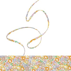 May include: A floral patterned fabric with a yellow background and small orange, pink, and blue flowers. A thin, curved strip of the same fabric floats above the main section, creating a dynamic visual.