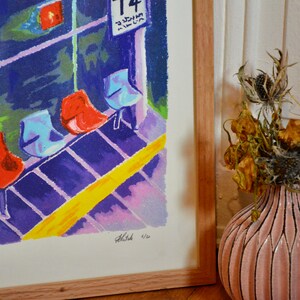 Puede incluir: Una impresi&oacute;n enmarcada de una pintura colorida que representa una fila de sillas rojas y azules en una sala de espera. La pintura est&aacute; firmada y numerada 4/20. La impresi&oacute;n est&aacute; colgada en una pared junto a un jarr&oacute;n con flores secas.