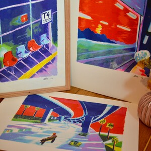Puede incluir: Tres impresiones de arte enmarcadas con dise&ntilde;os abstractos coloridos. La impresi&oacute;n superior izquierda presenta un fondo azul y morado con sillas rojas y una l&iacute;nea amarilla. La impresi&oacute;n superior derecha presenta una puesta de sol roja y naranja con un cielo azul y morado. La impresi&oacute;n inferior presenta un paso subterr&aacute;neo azul y morado con un cielo rojo y palmeras.