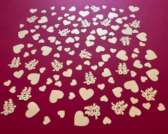 May include: A collection of gold-colored heart-shaped and Chinese double happiness symbol cutouts scattered on a deep red background. The hearts vary in size, creating a visually appealing pattern, suitable for wedding or celebratory decorations.