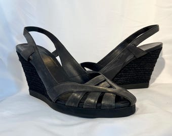May include: Black leather wedge sandals with a woven platform and an open toe design.