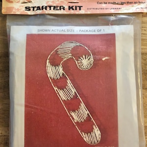 May include: A "Color String Art Starter Kit" featuring a candy cane design. The kit includes a red background with a silver string candy cane design. The package reads "Candy Cane" and "Style 013".