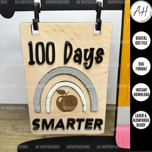May include: A wooden sign with the text "100 Days Smarter" in black lettering. The sign features a rainbow design with a red apple in the centre. The sign is designed for laser cutting and is available as a digital download.