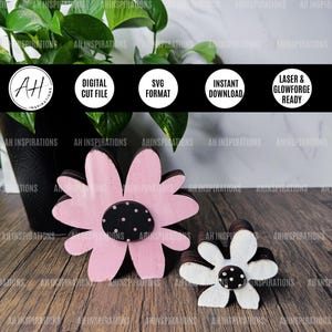 Könnte beinhalten: Zwei Holzblumenformen, eine rosa und eine weiße, mit schwarzen Punkten in der Mitte. Die Blumen sind übereinander gelegt und haben einen Used-Look. Das Bild enthält Text, der "Digitaler Schnittdatei", "SVG-Format", "Sofortiger Download" und "Laser- und Glowforge-Ready" lautet.