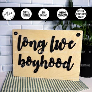 May include: A wooden sign with the phrase "long live boyhood" in black cursive lettering. The sign has a light wood grain finish and is mounted with black hardware. The top of the image includes circular icons with text: "Digital Cut File", "SVG Format", "Instant Download", and "Laser & Glowforge Ready".