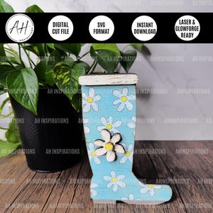May include: A blue and white wooden boot planter with a daisy pattern. The boot is sitting on a wooden surface.