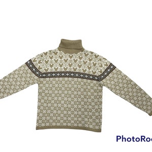 Puede incluir: Un suéter beige de cuello alto con un patrón geométrico blanco y marrón y siluetas de Mickey Mouse.