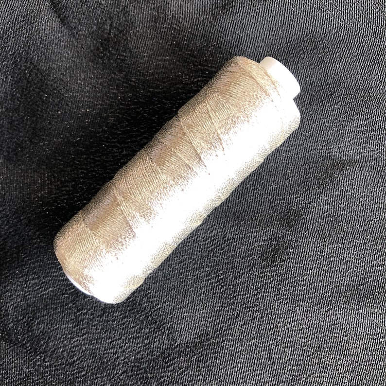Pu&ograve; includere: Un'bobina di filo metallico argentato.