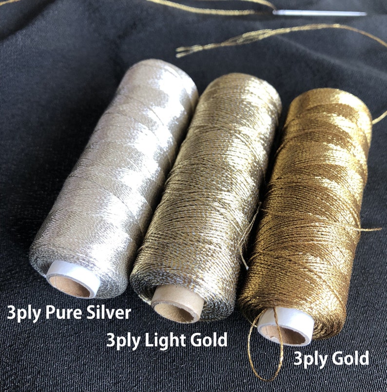 Pu&ograve; includere: Tre bobine di filo metallico, da sinistra a destra: 3 fili d'argento puro, 3 fili d'oro chiaro e 3 fili d'oro.