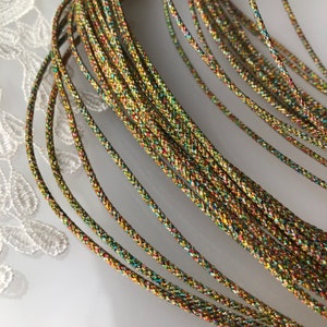 May include: A close-up of a bundle of iridescent gold cord. The cord is made of a braided material with a metallic sheen. The cord is ideal for crafting and jewellery making.