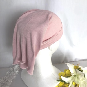 May include: A pink knitted beanie hat with a folded brim. The hat is on a white mannequin head.