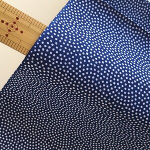 May include: A close-up of a blue fabric with a white polka dot pattern. The fabric has a subtle wave-like texture.