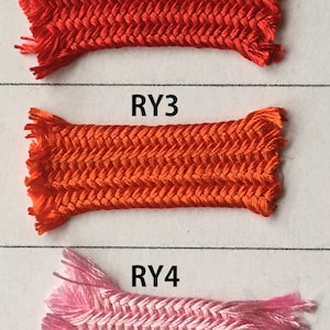 May include: Five samples of braided cord in various colors: orange, red, light orange, pink, and gold. Each sample is rectangular with a herringbone pattern and frayed ends. The samples are labeled RY1 through RY5.