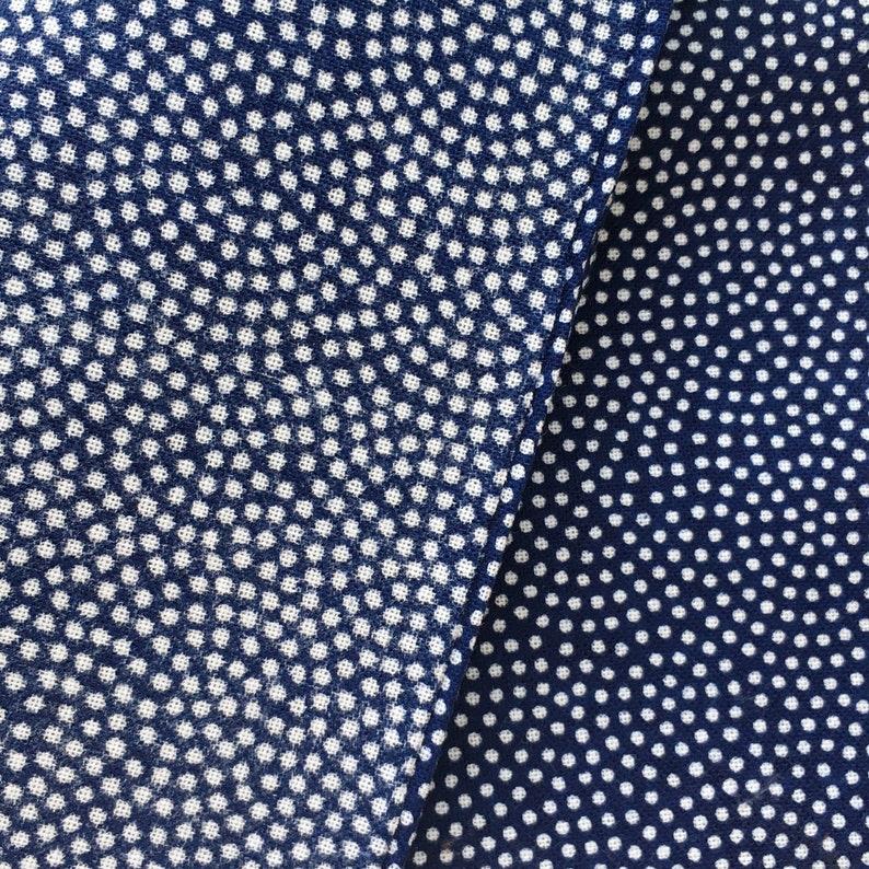 May include: Two pieces of blue fabric with a white polka dot pattern. The fabric on the left has a slightly larger polka dot pattern than the fabric on the right.